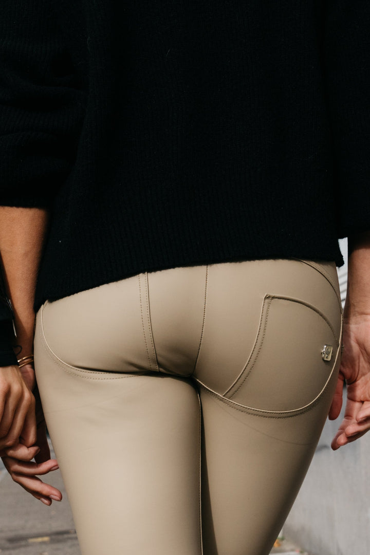 Person wearing beige pants with a black top, standing against a blurred background