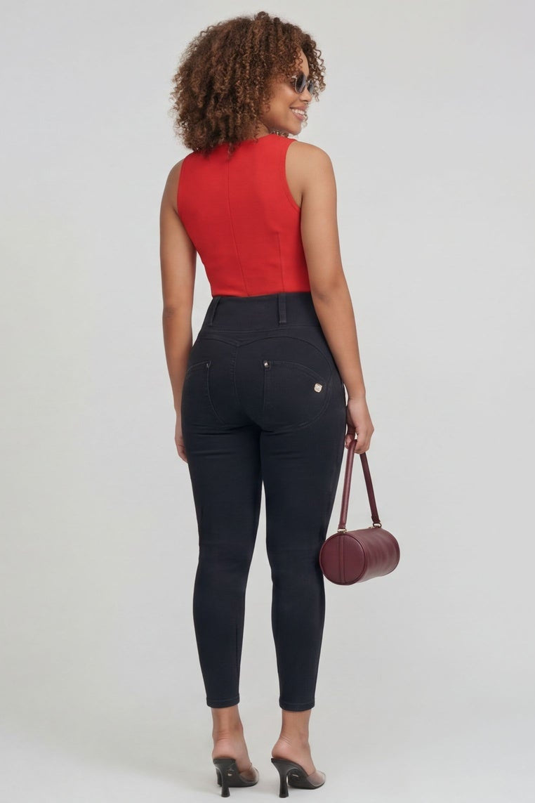 Woman wearing a red top and black pants, holding a brown handbag, on a white background.