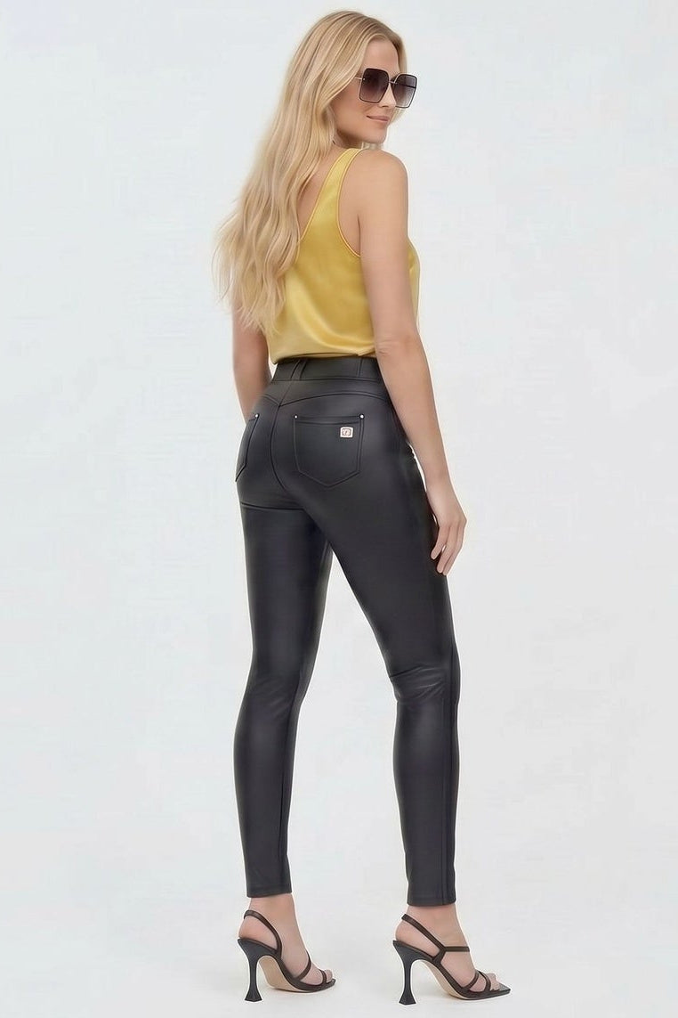 Woman wearing a yellow top and black leather pants on a white background