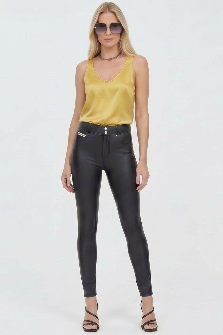 Woman wearing a yellow top and black leather pants on a white background