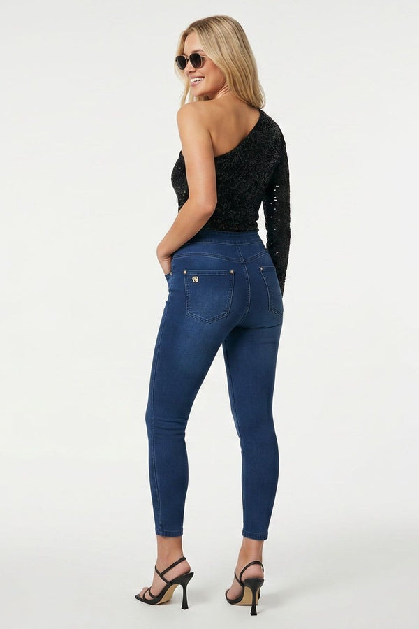 Woman wearing blue jeans and a black top on a white background