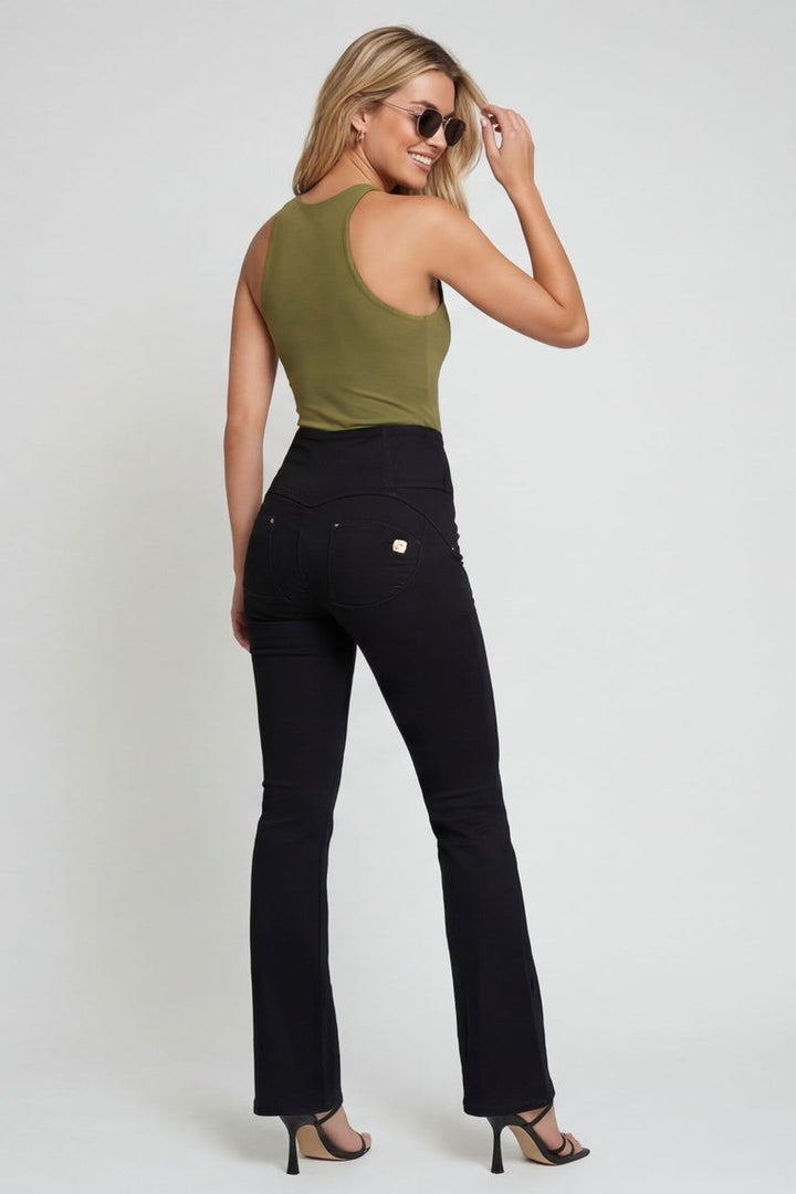 Woman wearing a green top and black pants on a white background