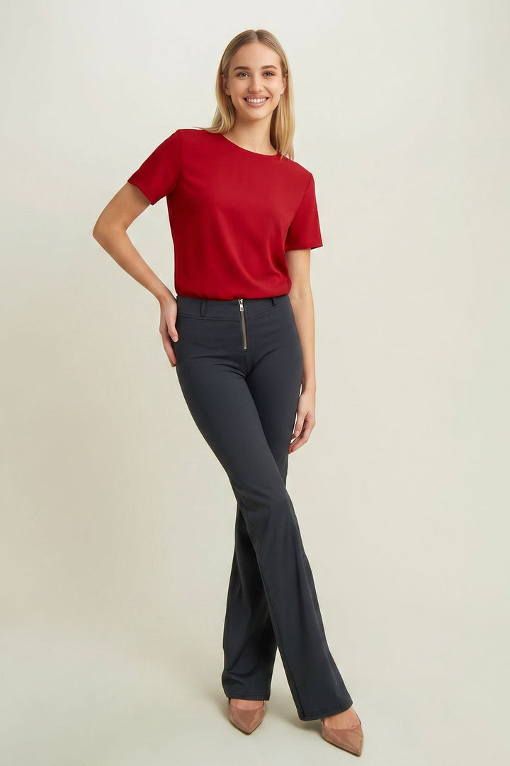 Woman wearing a red top and dark blue pants on a beige background