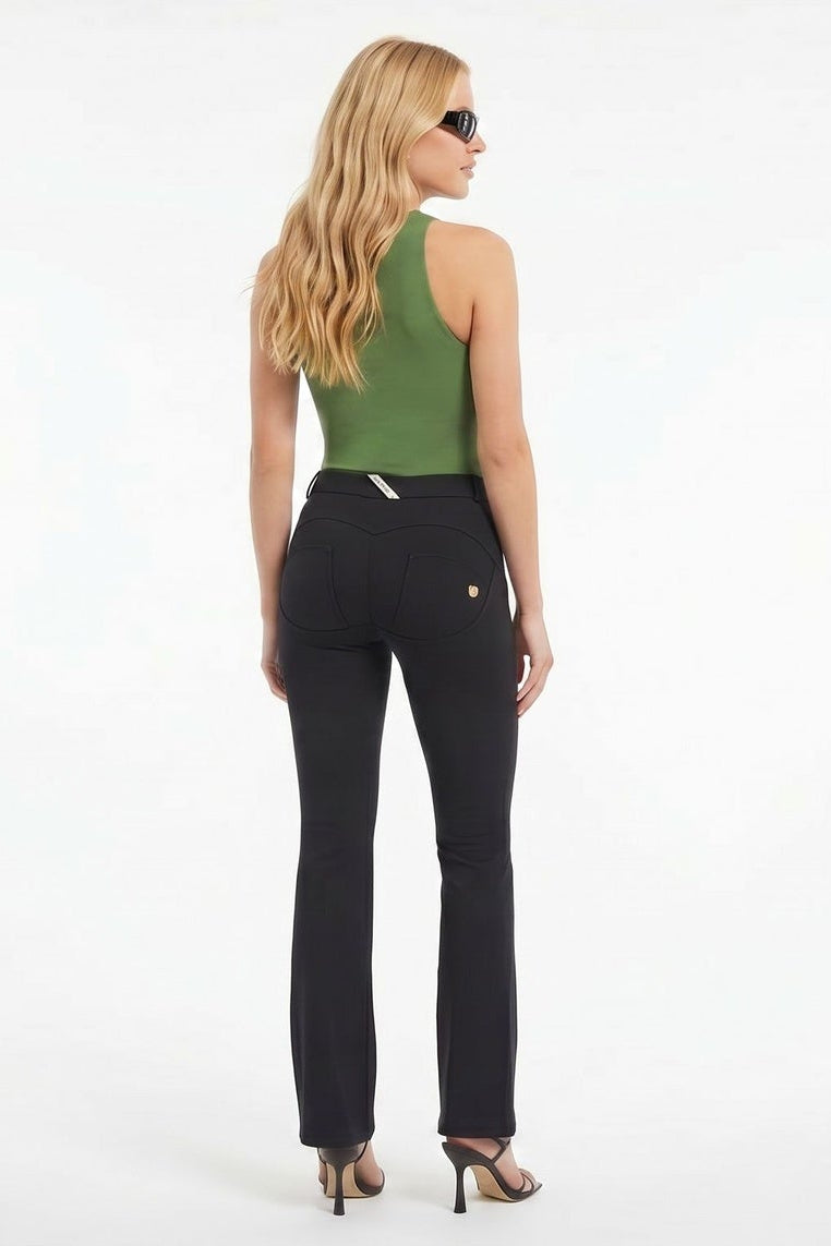 Woman wearing a green top and black pants on a white background