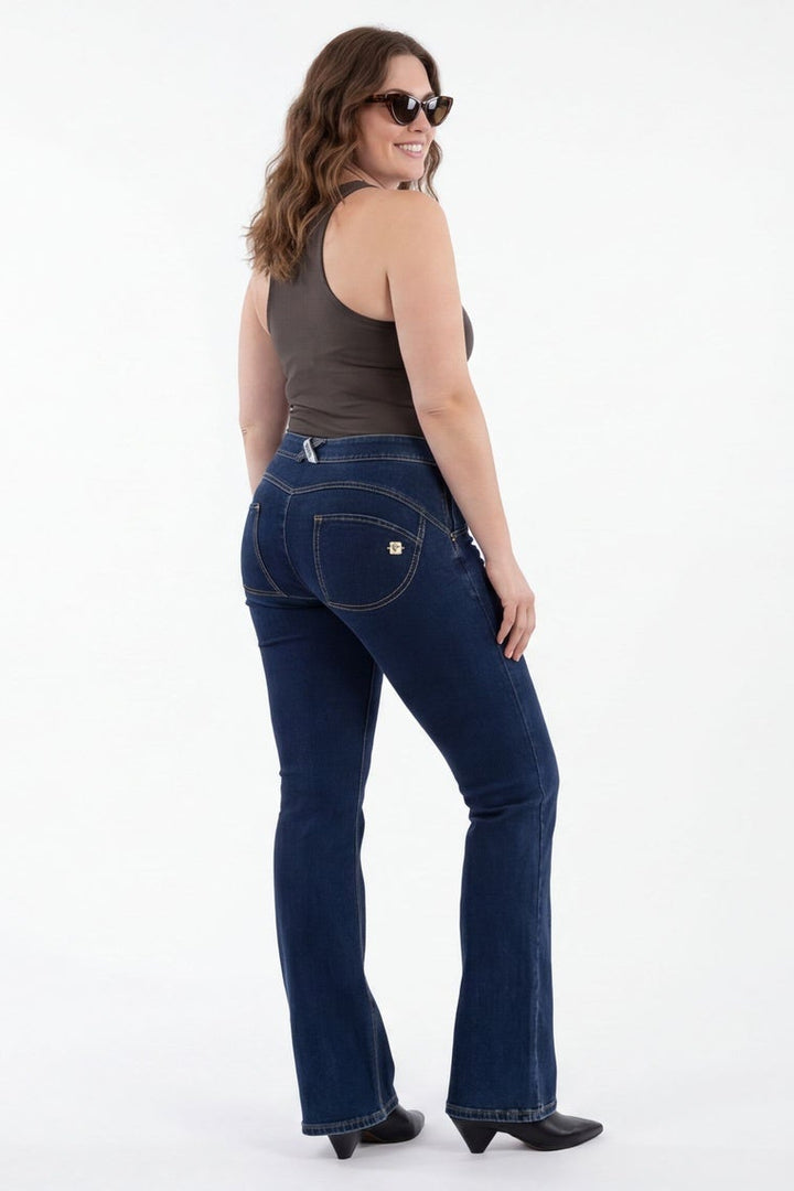 Woman modeling dark blue jeans from front and back views on a white background