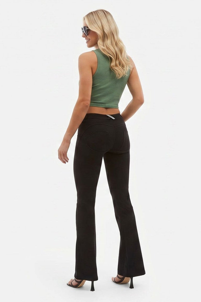 Woman wearing a green crop top and black pants on a white background