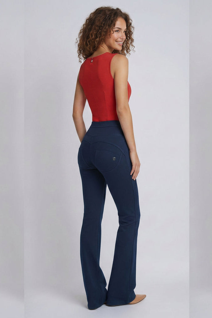 Woman wearing a red top and navy blue flared pants on a white background