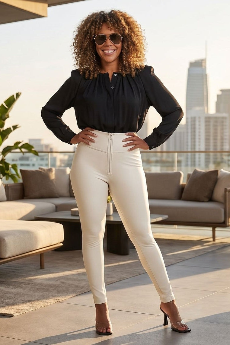 Woman in black top and white pants standing on a rooftop with city skyline in the background