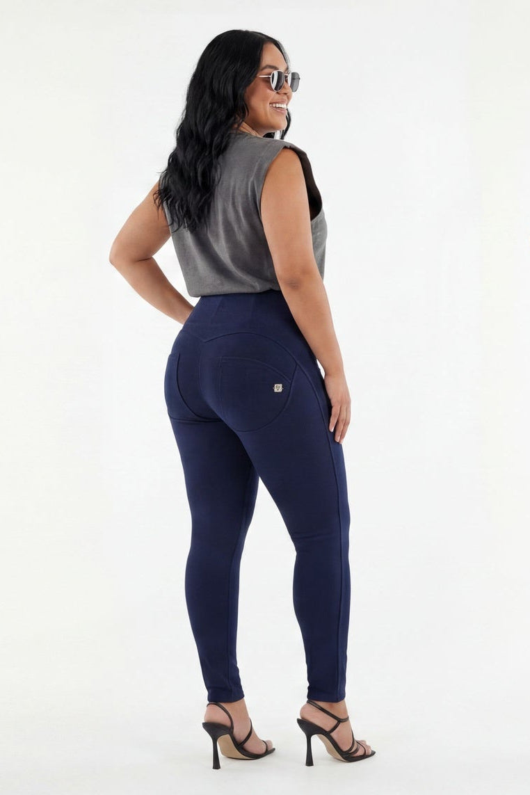 Woman wearing a gray sleeveless top and navy leggings on a white background