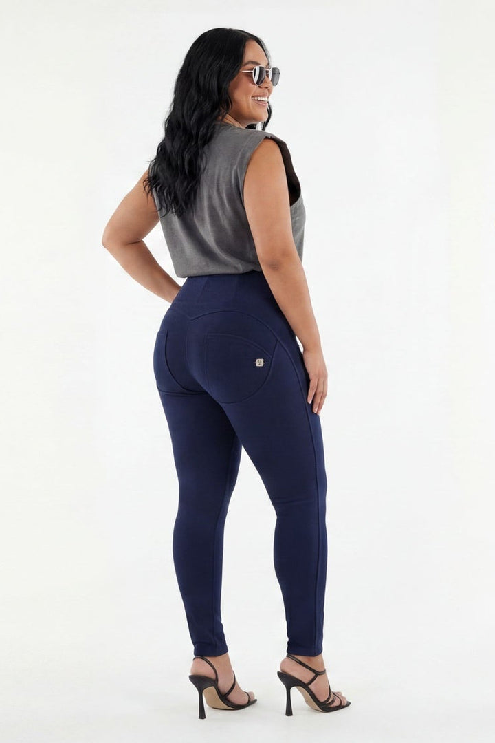 Woman wearing a gray sleeveless top and navy leggings on a white background
