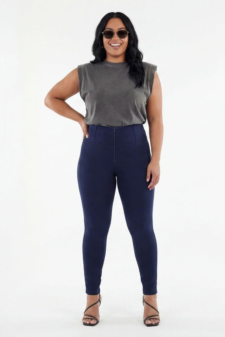 Woman wearing a gray sleeveless top and navy leggings on a white background
