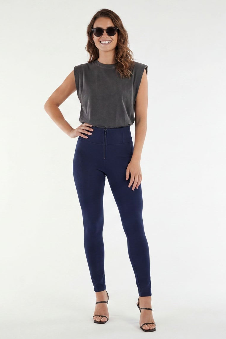Woman wearing navy leggings and a gray top on a white background