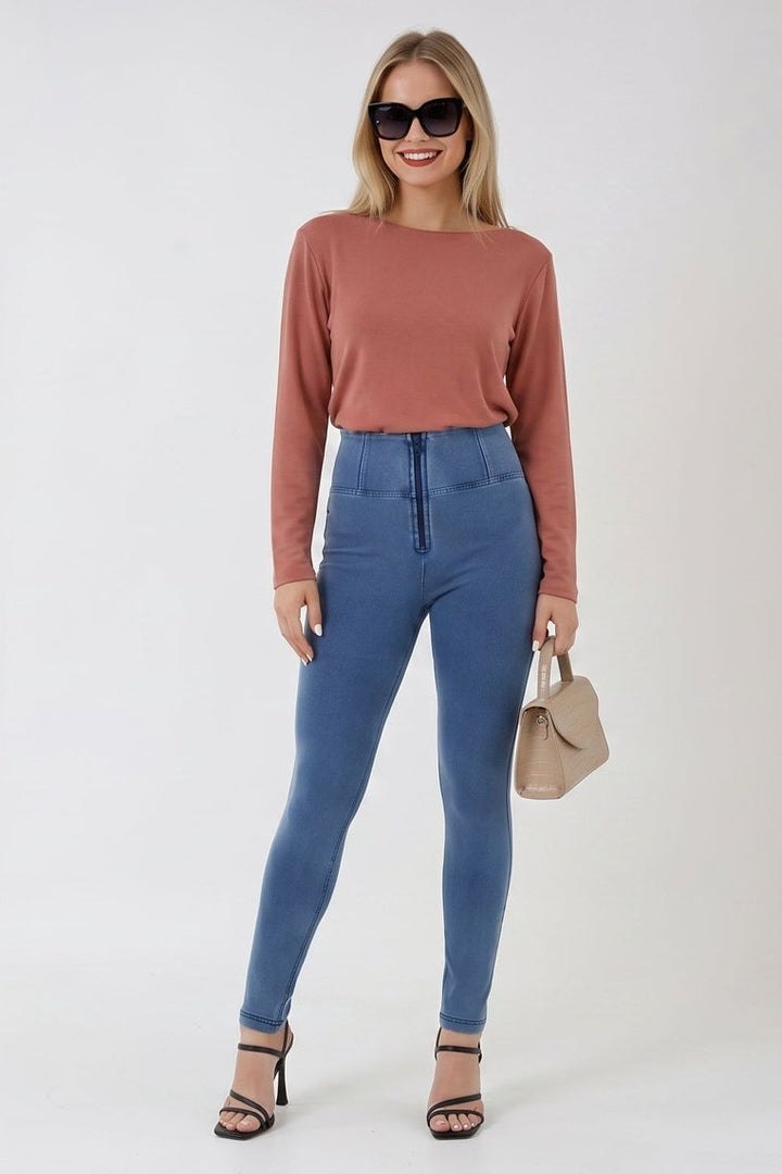 Woman wearing a pink sweater and blue jeans on a white background