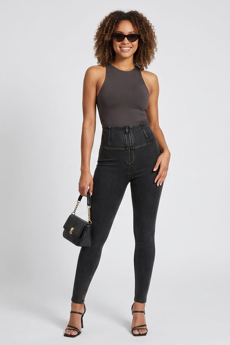 Woman wearing a gray sleeveless top and black jeans with sunglasses and a handbag on a white background