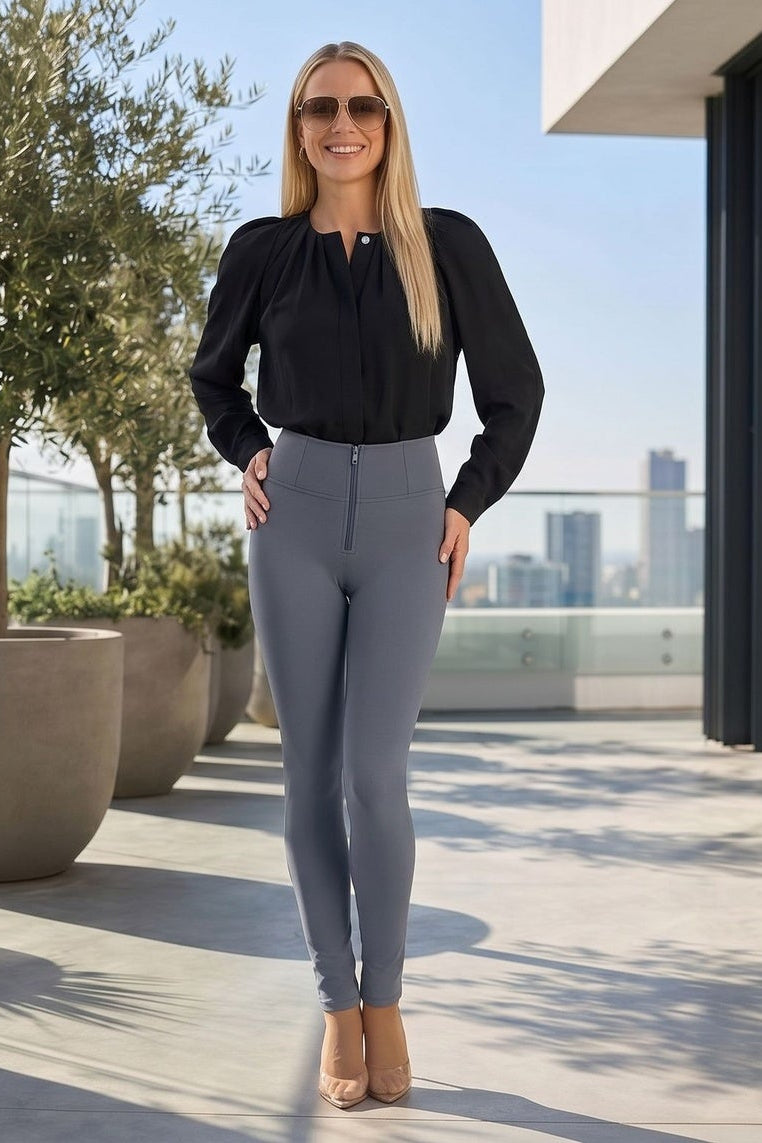 Woman in black top and gray leggings standing on a rooftop with city skyline view.