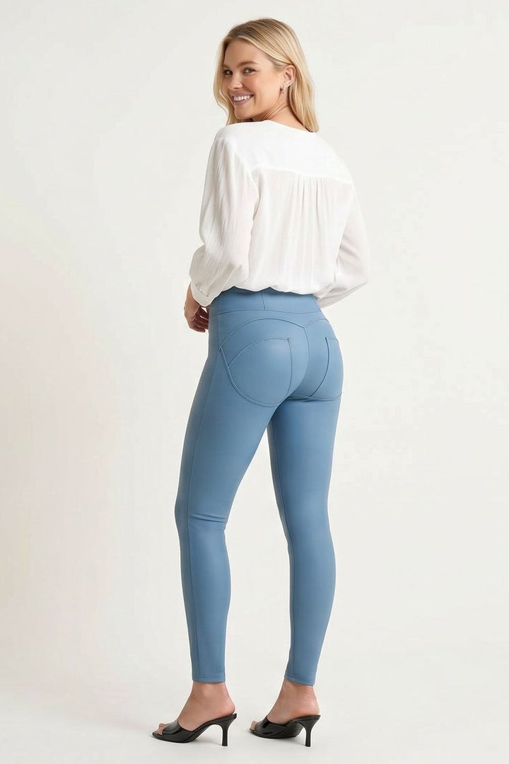 Woman wearing light blue jeans and a white blouse on a plain background