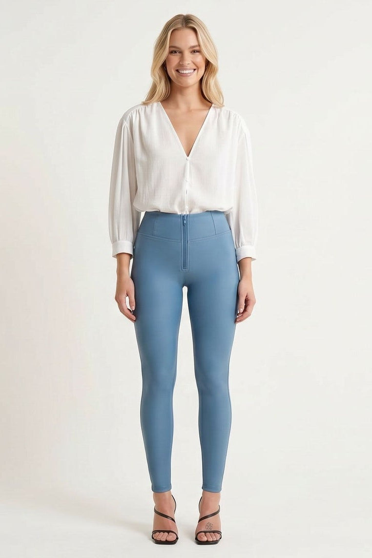 Woman wearing light blue jeans and a white blouse on a plain background