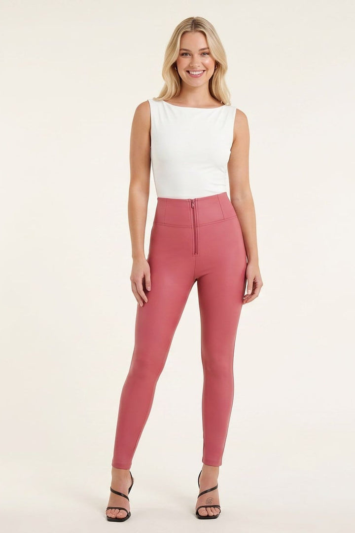Woman wearing pink leggings and a white top on a plain background