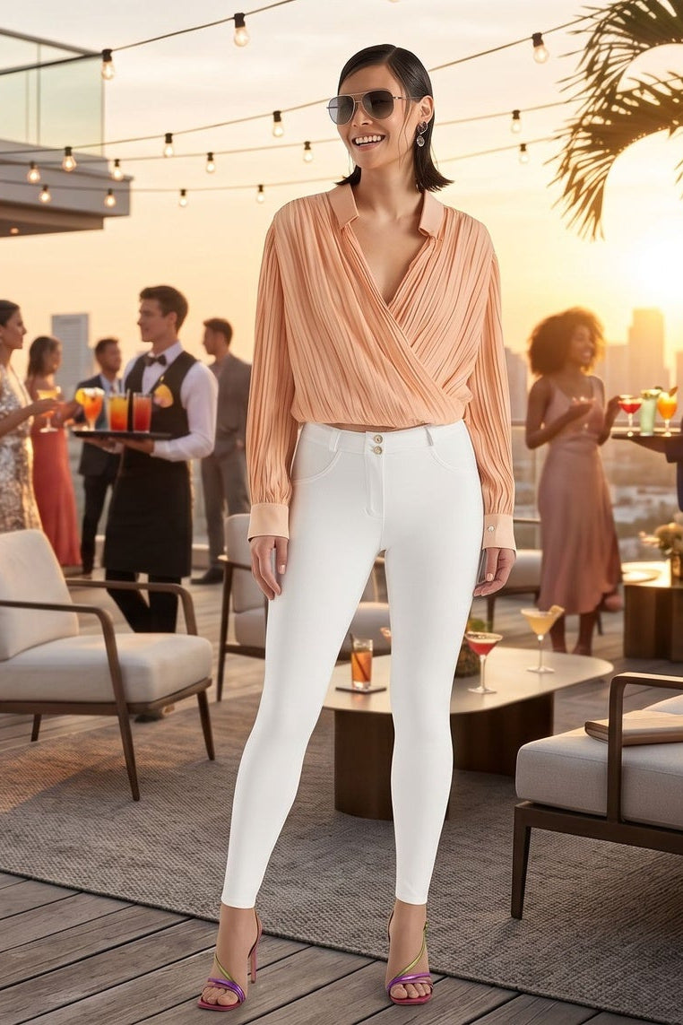 Two women in matching outfits walking on a wooden deck with a sunset and cityscape background.