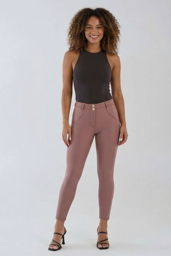 Woman wearing a dark gray tank top and pink pants on a white background