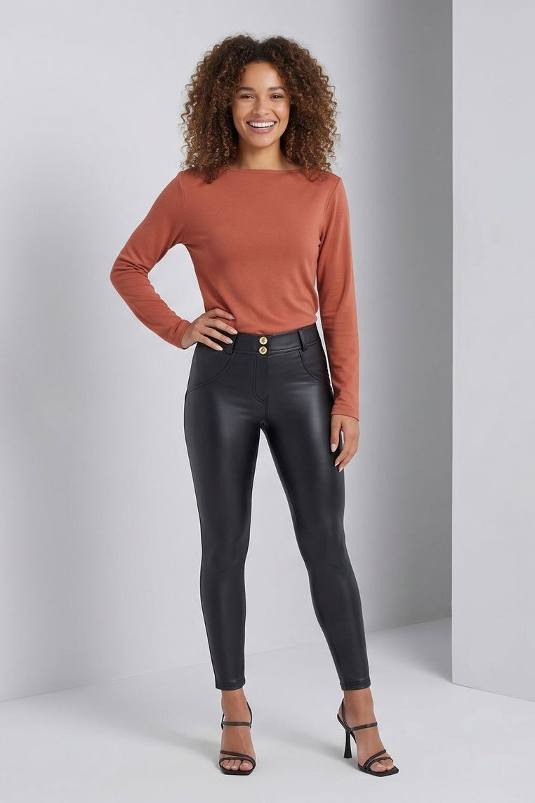 Woman wearing black leather pants in front of a gray background