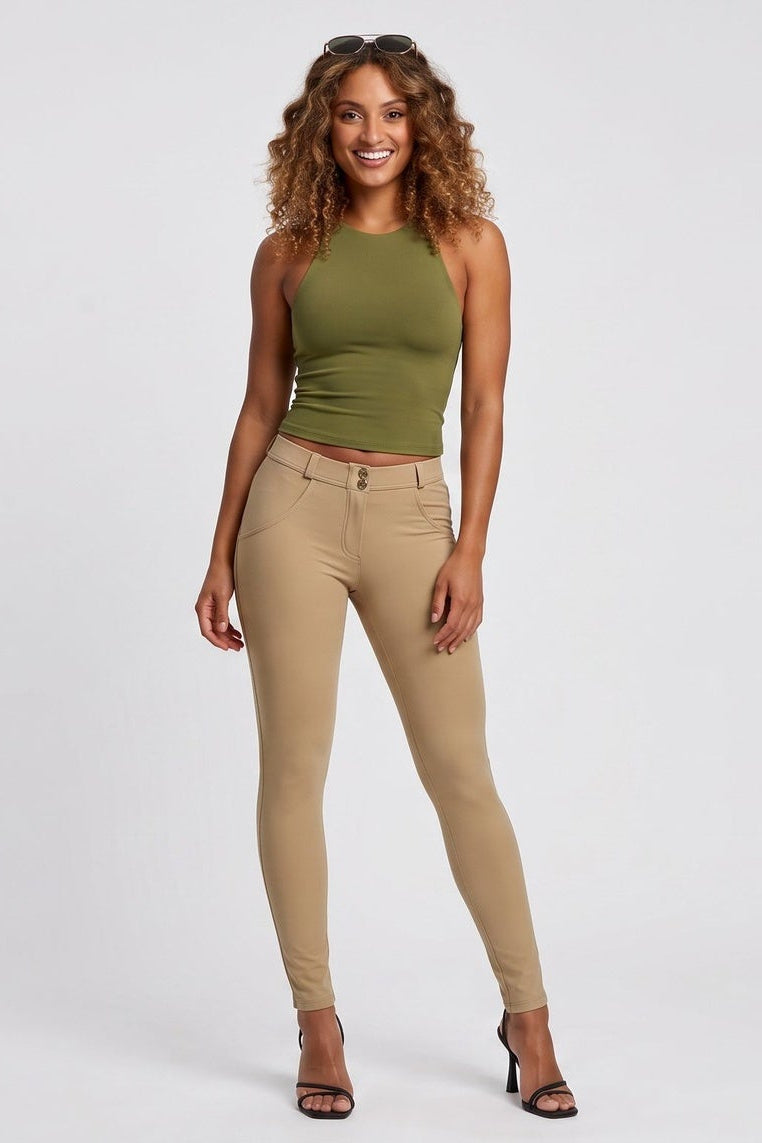 Woman wearing a green top and beige pants on a white background
