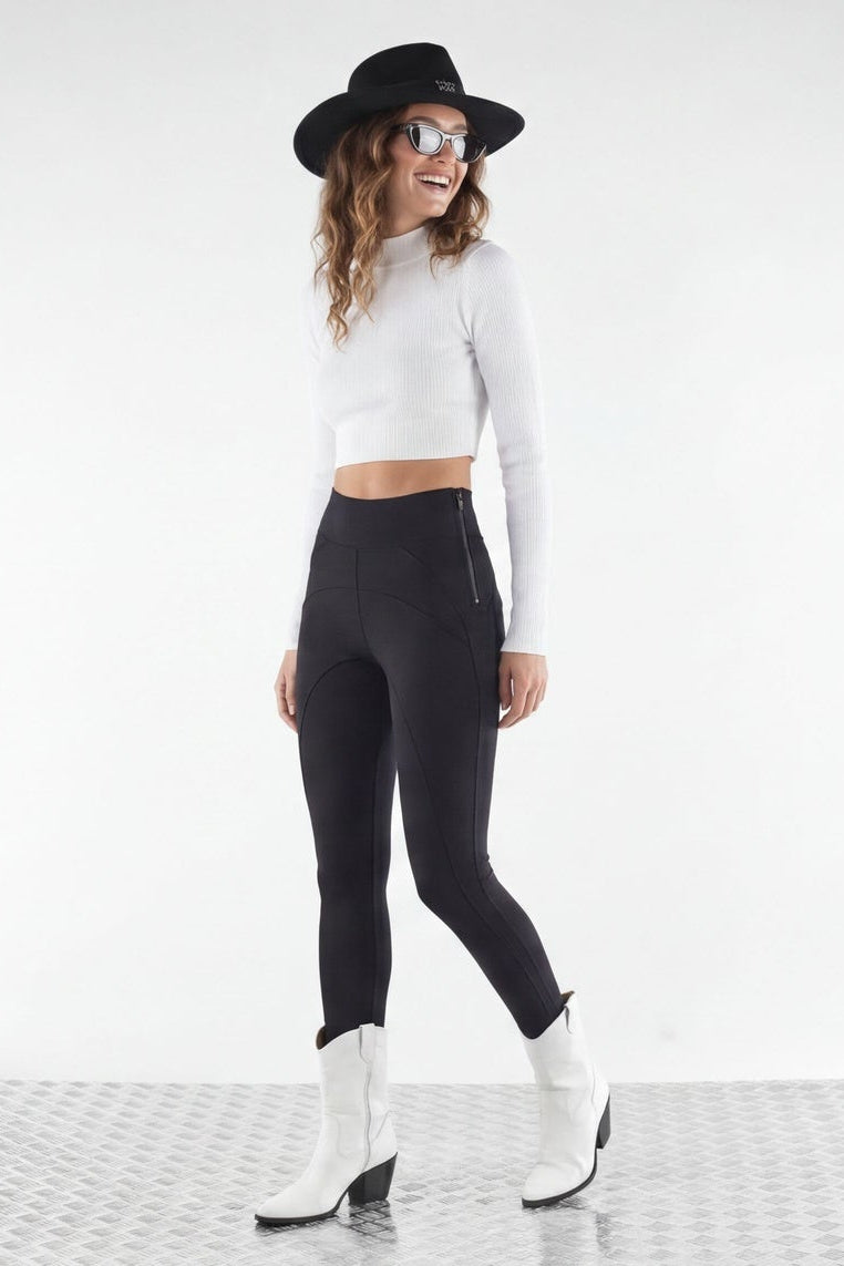 Woman wearing a white top, black leggings, and white boots with a black hat on a white background