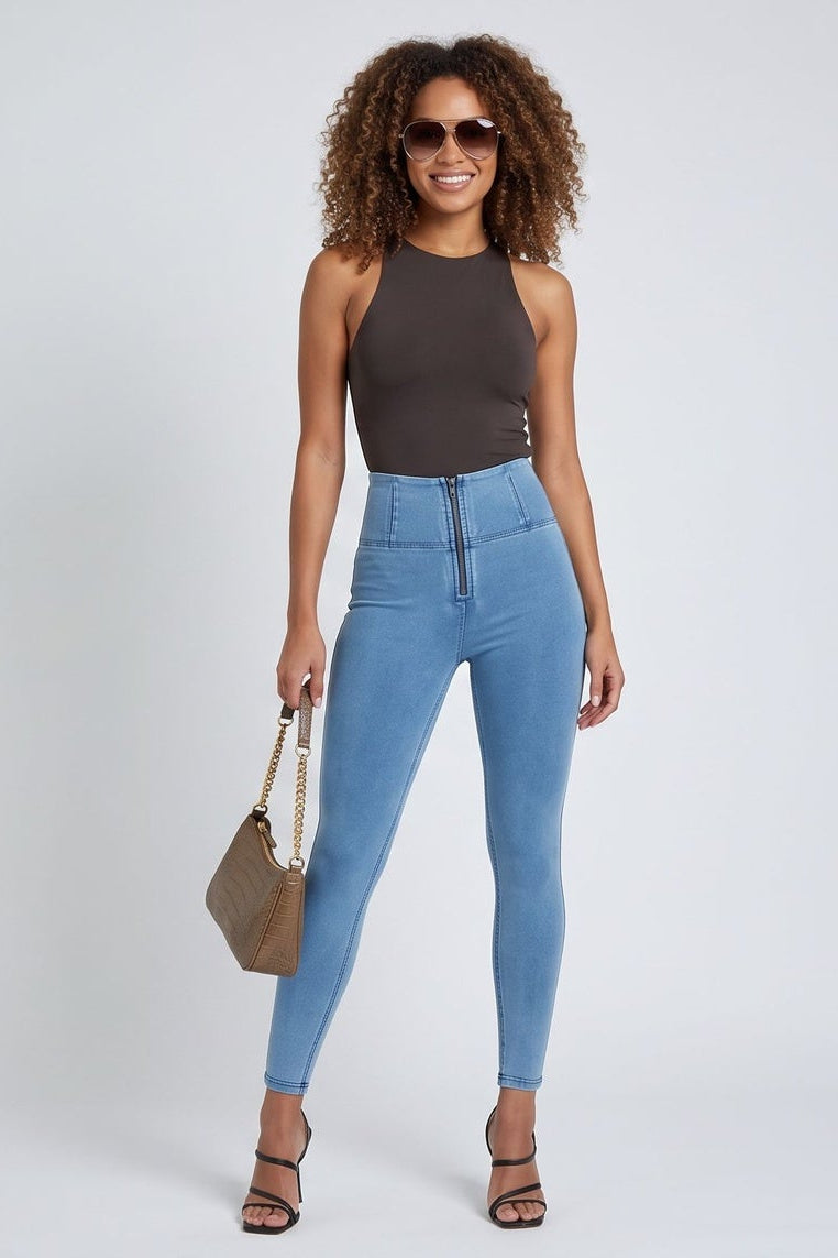 Woman wearing blue jeans and a black top, holding a beige handbag, on a white background.