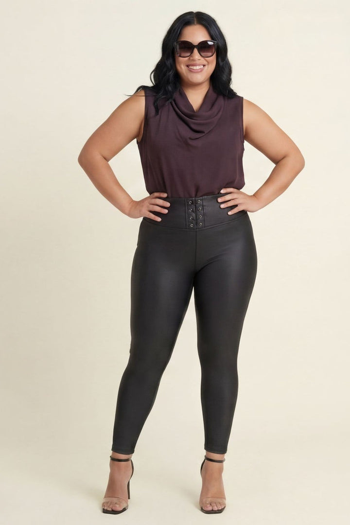 Woman wearing black leather leggings and a maroon top on a beige background