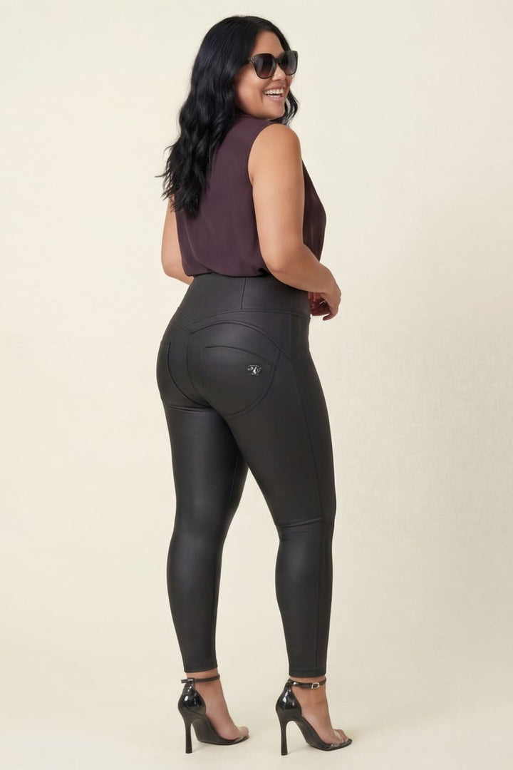Woman wearing black leather leggings and a maroon top on a beige background