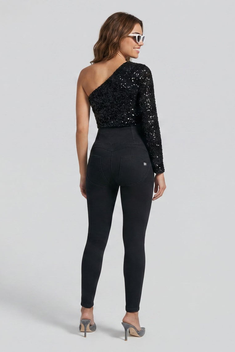 Woman wearing a black one-shoulder jumpsuit with sequins on a white background