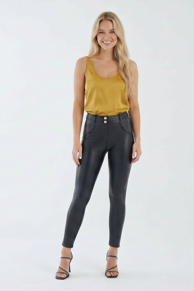 Woman wearing black leggings and a mustard top on a white background
