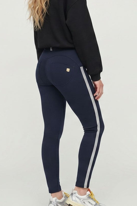 Woman wearing a black sweatshirt and navy pants with white stripes, standing against a white background.