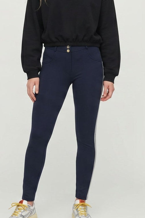 Woman wearing a black sweatshirt and navy pants with white stripes, standing against a white background.