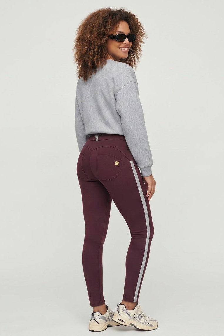 Woman wearing a gray sweatshirt and maroon leggings with white stripes on a white background