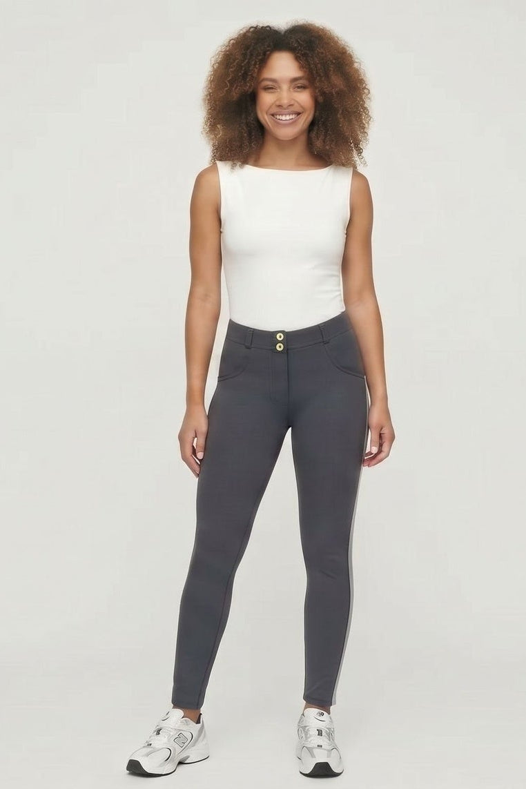 Woman wearing a white top and dark gray leggings with white stripes on a white background