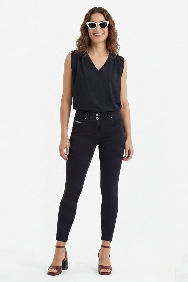 Woman wearing black sleeveless top and pants on a white background