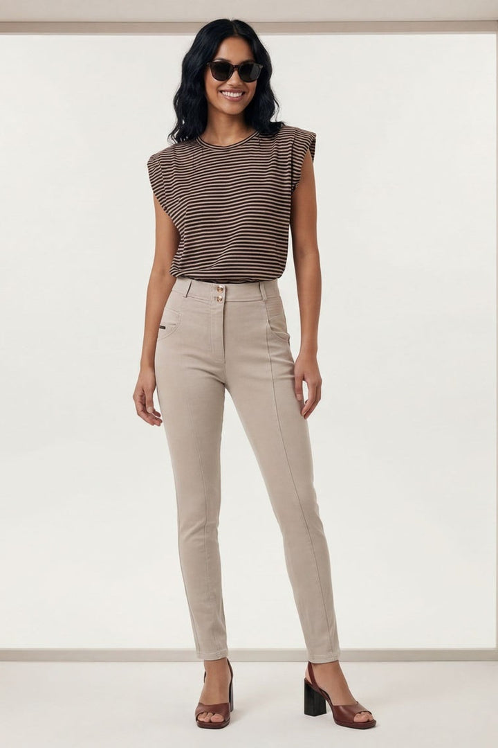 Woman wearing a brown top and beige pants in a minimalistic setting