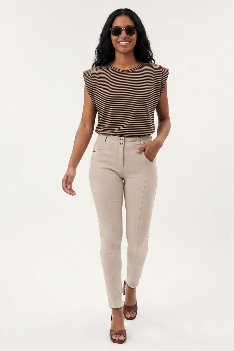 Woman modeling beige pants and a striped top on a white background