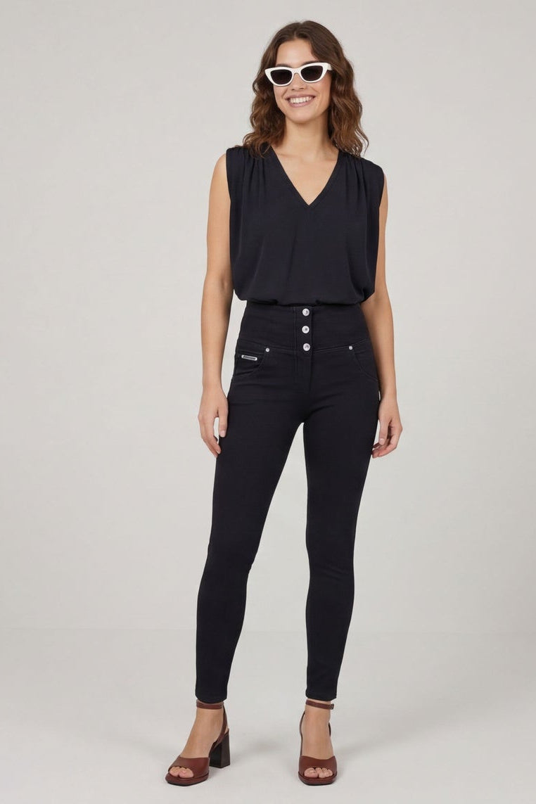 Woman wearing a black sleeveless top and black pants, standing against a plain background.
