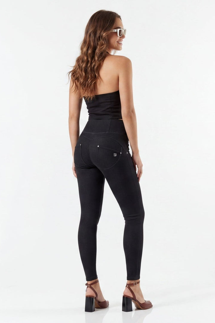 Woman modeling black high-waisted jeans from front and back on a white background
