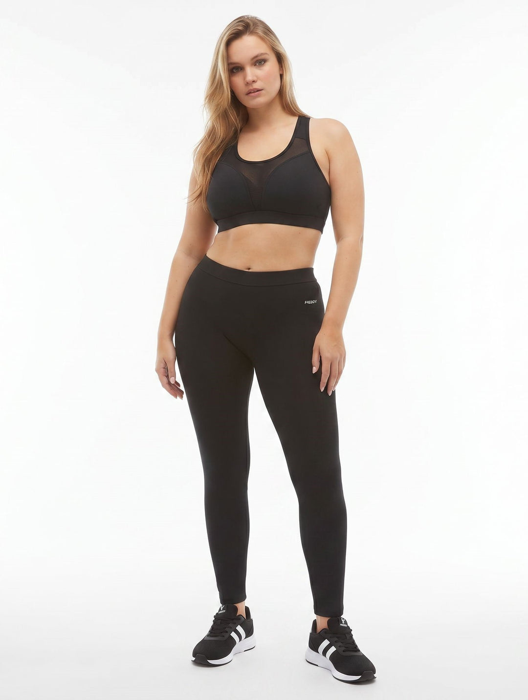Woman wearing a black sports bra and leggings on a white background