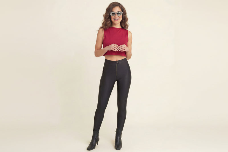 Woman wearing a red top and black leggings on a plain background