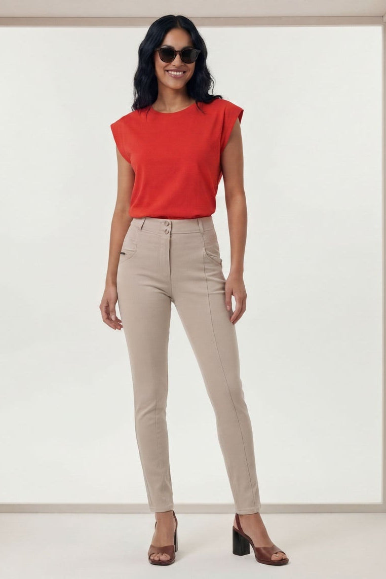 Woman wearing a red top and beige pants in a minimalistic setting